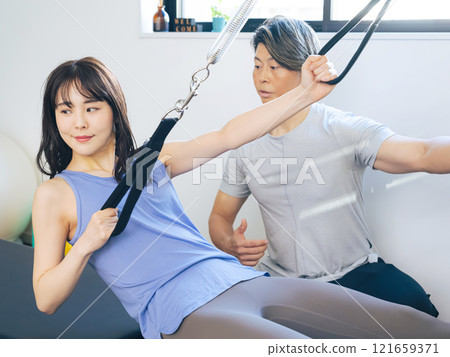 A woman taking a machine pilates lesson A woman taking a machine pilates lesson 121659371