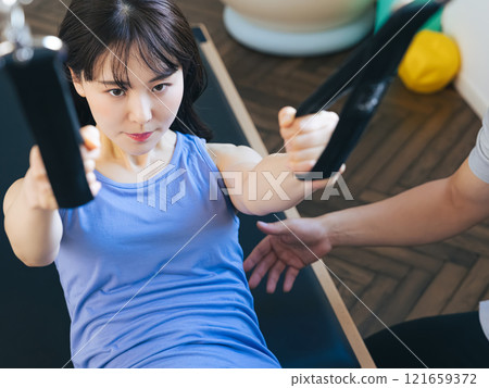 A woman taking a machine pilates lesson A woman taking a machine pilates lesson 121659372