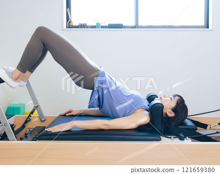 Woman doing machine pilates training Woman doing machine pilates training 121659380