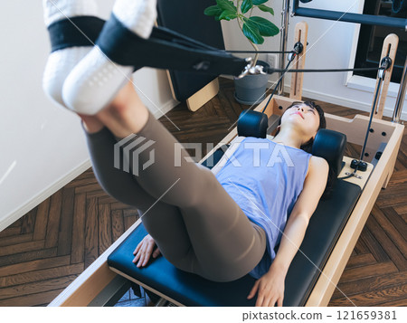 Woman doing machine pilates training Woman doing machine pilates training 121659381