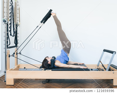 Woman doing machine pilates training Woman doing machine pilates training 121659396