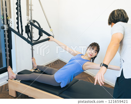 A woman taking a machine pilates lesson A woman taking a machine pilates lesson 121659421