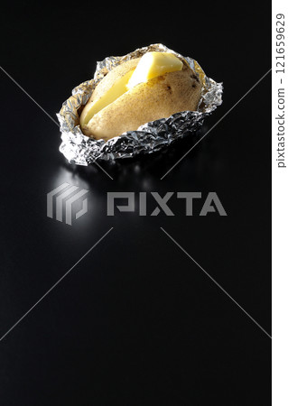 Photographing buttered potatoes on a black background 121659629