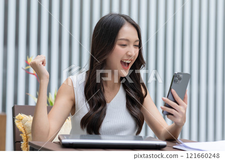 Millennial asian young woman looking mobile phone laughing with good news or discount voucher for shopping online at home.Happy and cheerful woman looking on cellphone app read message feel excited Millennial asian young woman looking mobile phone laughing with good news or discount voucher for shopping online at home.Happy and cheerful woman looking on cellphone app read message feel excited 121660248