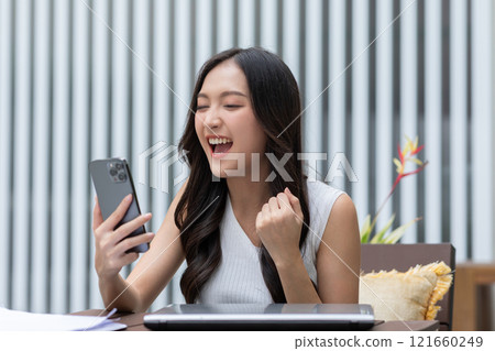 Millennial asian young woman looking mobile phone laughing with good news or discount voucher for shopping online at home.Happy and cheerful woman looking on cellphone app read message feel excited Millennial asian young woman looking mobile phone laughing with good news or discount voucher for shopping online at home.Happy and cheerful woman looking on cellphone app read message feel excited 121660249