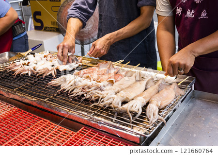 Close-up of the vendors grilling squid skewers at the night market in Taiwan.  121660764