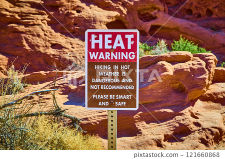 Desert Heat Warning Sign with Red Rock Formations Eye-Level View 121660868