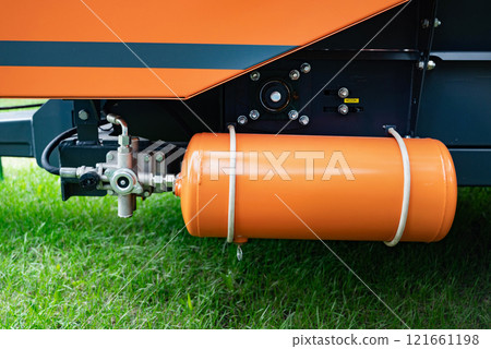 Close-up of orange gas cylinder attached to machinery. Close-up of orange gas cylinder attached to machinery. 121661198