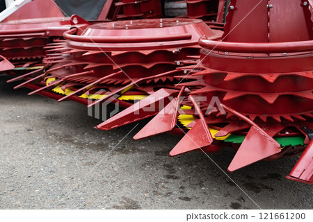 Close-up of red agricultural machinery on a paved surface. Close-up of red agricultural machinery on a paved surface. 121661200