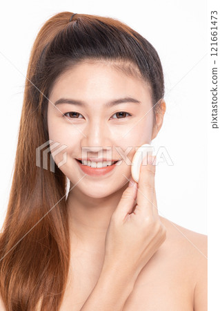 Smiling Asian woman applying foundation with a cosmetic sponge on a white background Smiling Asian woman applying foundation with a cosmetic sponge on a white background 121661473