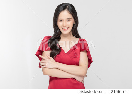 Radiant young woman smiling confidently in a stylish red dress with a white background Radiant young woman smiling confidently in a stylish red dress with a white background 121661551