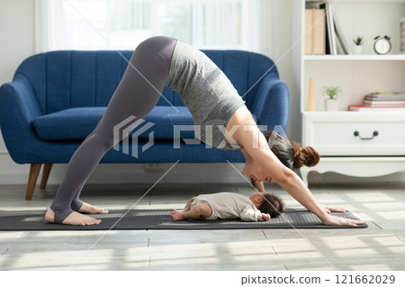 Side view of Wellness Asian woman mom doing yoga Downward Facing dog with baby at cozy home.Happy healthy mother yoga exercise newborn baby boy sleep and lying at warmth place. Mom and Baby Concept 121662029