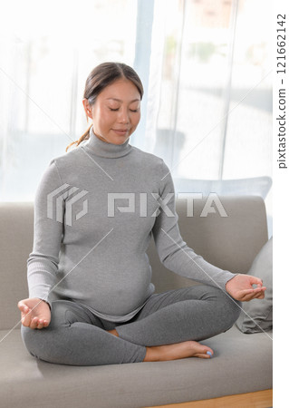 Asian Pregnant Woman Practicing Meditation at Home for Wellbeing Asian Pregnant Woman Practicing Meditation at Home for Wellbeing 121662142