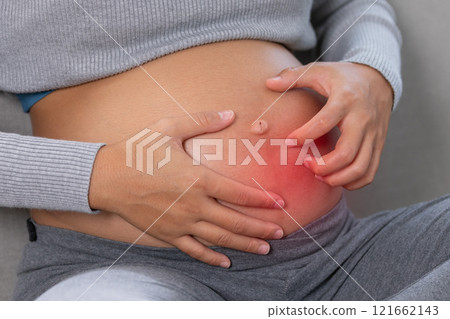 Close up of a pregnant woman scratching her itchy belly, highlighting common skin discomforts during pregnancy Close up of a pregnant woman scratching her itchy belly, highlighting common skin discomforts during pregnancy 121662143