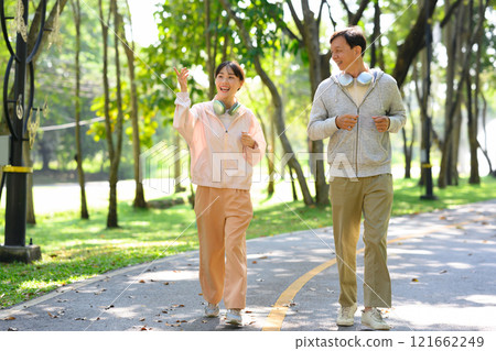 Happy an older man and his daughter enjoying their exercise routine, jogging together through a park path 121662249