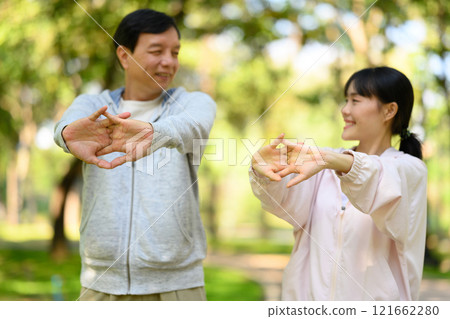 Happy father and daughter warming up for their morning workout in a serene park 121662280