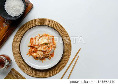 Traditional Kimchi dish placed on a rustic woven placemat surrounded by essential ingredients Traditional Kimchi dish placed on a rustic woven placemat surrounded by essential ingredients 121662310