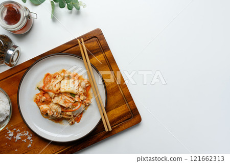 Traditional Korean Kimchi on a rustic Plate accompanied by wooden chopsticks. Korean cuisine and traditional side dish concept Traditional Korean Kimchi on a rustic Plate accompanied by wooden chopsticks. Korean cuisine and traditional side dish concept 121662313