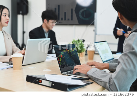 Group of coworkers in a meeting, focusing on data analytics and market trends 121662379