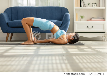 Asian woman finding peace and balance through yoga practice in the comfort of her home. Promoting wellness, mindfulness, and self care. Perfect for yoga and home wellness concepts 121662911