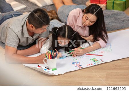 Heartwarming scene of Asian family spending quality time together at home. The father, mother, and their young daughter are lying on the floor 121663203