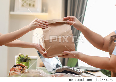 close up shot capturing moment customer receives brown paper bag from chef during a food exchange. focuses on the hands holding the bag, symbolizing the personal touch and care in food service close up shot capturing moment customer receives brown paper bag from chef during a food exchange. focuses on the hands holding the bag, symbolizing the personal touch and care in food service 121663270
