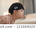 Asian cheerful young boy with Down syndrome enjoys playing with bubbles indoors. His bright smile and playful gestures capture the innocence and joy of childhood 121664020