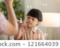 Asian cheerful young boy with Down syndrome enjoys playing with bubbles indoors. His bright smile and playful gestures capture the innocence and joy of childhood 121664039