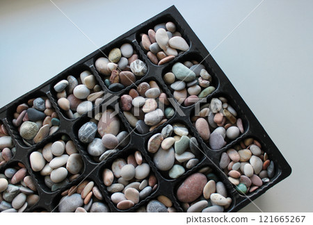 Same Cells Of Cellular Box Full Of Smooth Pebbles On White Surface Top View Same Cells Of Cellular Box Full Of Smooth Pebbles On White Surface Top View 121665267