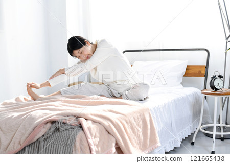 Young woman stretching on the bed 121665438