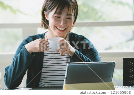 Woman sitting on terrace with tablet device 121665908