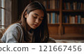 A young girl engrossed in a book at the library 121667456