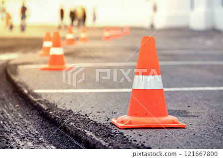 road repairs Multiple orange traffic cones placed in a line on an asphalt street, indicating roadwork or caution area. 121667800