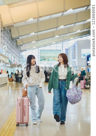 Two women walking through the airport 121668081
