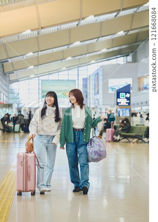 Two women walking through the airport 121668084