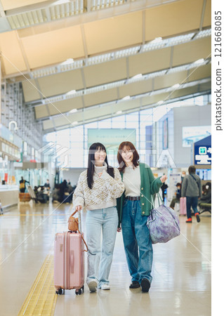 Two women walking through the airport 121668085