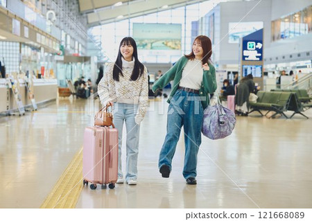 Two women walking through the airport 121668089