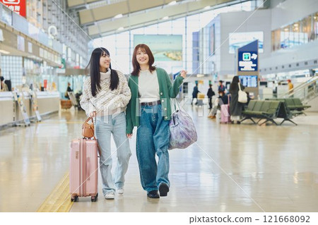 Two women walking through the airport 121668092