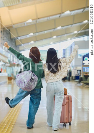 Two women walking through the airport 121668116