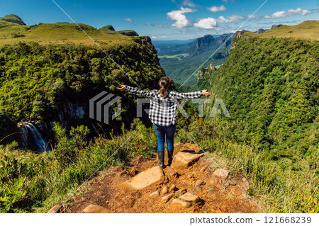 Woman enjoying picturesque landscape and staying on cliff in Espraiado Canyon in Santa Catarina, Brazil. 121668239