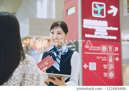 一名婦女在機場接受地勤人員的指導 一名婦女在機場接受地勤人員的指導 121669486