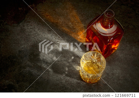 Bottle and crystal glass of whiskey on a stone table. 121669711