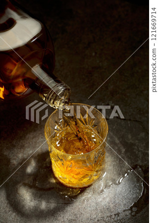 Whisky pour from a bottle into a crystal glass. 121669714