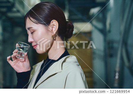 A woman tasting sake at a sake brewery A woman tasting sake at a sake brewery 121669954
