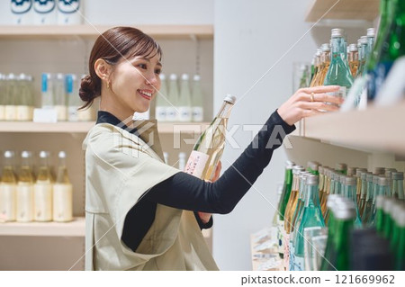 A woman choosing alcohol at a store. Photo courtesy of Imayo Tsukasa Sake Brewery. 121669962
