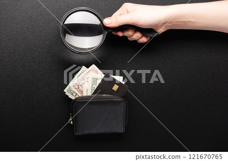 Checking money. Money and magnifying glass in hands. Examining money. Black background. 121670765