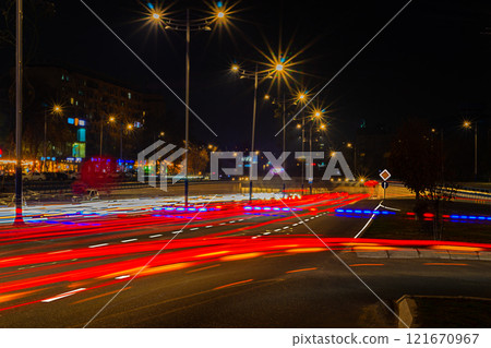 Night photography with a long exposure of a multi-lane road with an exit on which many cars are moving and leaving lines from the headlights and lights of marker and brake. Evening traffic jams 121670967