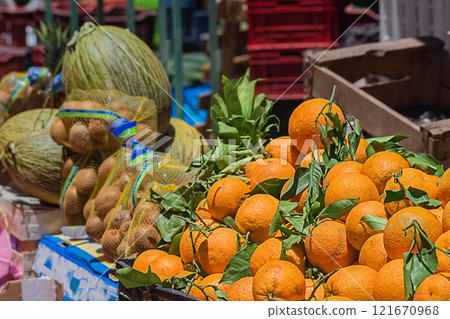 Fruit stalls: oranges, kiwis, pineapples, melons at the outdoor street market in the sunshine. Sale of organic plant-based food products at affordable prices. Fair, oriental bazaar 121670968