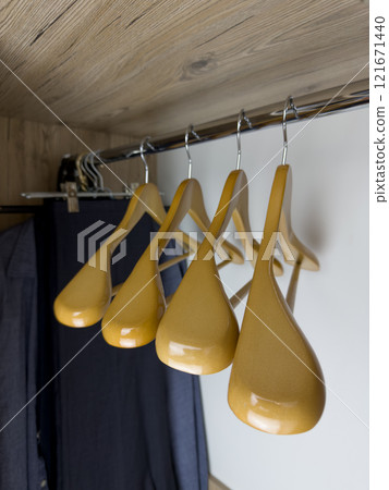 Vertical photography of empty wooden hangers on crossbar in clothes closet, replenishing closet with new clothes, storage space for clothes in apartment, focus on hanger shoulder 121671440