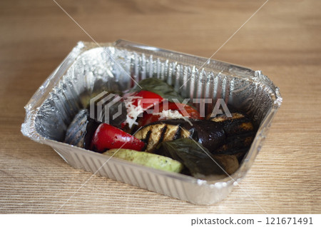 Grilled vegetables in foil box on wooden table Grilled vegetables in foil box on wooden table 121671491